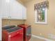 Laundry room featuring modern red washer and dryer and white cabinets at 2554 Emerald Dr, Jonesboro, GA 30236