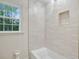 Bright bathroom featuring a white bathtub, tiled walls, and a window with natural light at 2958 Cravey Ne Dr, Atlanta, GA 30345