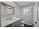 Grey bathroom featuring marble vanity, decorative mirror, toilet, and window at 2958 Cravey Ne Dr, Atlanta, GA 30345