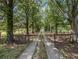 Long concrete driveway leading to a home, lined with mature trees and black fencing at 5809 Warren Farm Sw Rd, Powder Springs, GA 30127