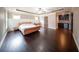 Bedroom featuring hardwood floors, a tray ceiling, wainscoting, and a bar area at 5825 Trailwood Ct, Suwanee, GA 30024