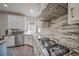 Well-equipped kitchen area featuring a cooktop and a stainless steel range hood, complemented by stylish backsplash and counters at 5825 Trailwood Ct, Suwanee, GA 30024