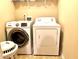 Bright laundry room featuring a full-size washer and dryer and a white storage shelf at 4125 Madison Bridge Dr, Suwanee, GA 30024