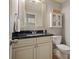 Cozy bathroom featuring a vanity with a black countertop, a decorative mirror, and a matching toilet at 3003 Maple Ln, Alpharetta, GA 30009