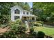 Two-story home with a covered front porch, surrounded by lush greenery and mature trees at 3003 Maple Ln, Alpharetta, GA 30009