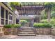 Multi-level stone patio with a pergola, lush greenery, and outdoor dining area offering a tranquil setting at 366 Blackland Nw Rd, Atlanta, GA 30342