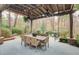 Spacious outdoor patio featuring a dining table under a pergola, surrounded by lush landscaping at 366 Blackland Nw Rd, Atlanta, GA 30342