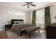 Well-lit bedroom with a ceiling fan, a large window with green curtains, and a tufted bench at the end of the bed at 2542 Warwick Ne Cir, Atlanta, GA 30345