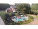 Aerial view of a backyard pool area with lounge seating, landscaping, and a brick home in a tree-lined neighborhood at 6745 Molly View Pt, Cumming, GA 30041