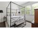 Bedroom featuring a metal canopy bed frame, large windows and wood floors at 9121 Selborne Ln, Chattahoochee Hills, GA 30268
