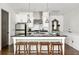 Open kitchen features stainless steel appliances, center island with dark countertops and bar stool seating at 9121 Selborne Ln, Chattahoochee Hills, GA 30268