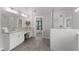 A well lit bathroom featuring double sinks, granite counters, wood look tile and a glass enclosed tiled shower at 4205 Rock Creek Dr, Cumming, GA 30028