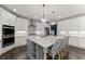 A stylish kitchen features white cabinetry, stainless steel appliances, a large island with barstool seating, and modern lighting at 4205 Rock Creek Dr, Cumming, GA 30028