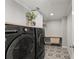 A modern laundry room with front-loading washer and dryer, patterned floor tiles, and a wooden folding countertop at 4205 Rock Creek Dr, Cumming, GA 30028