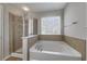 Bright bathroom featuring a soaking tub, glass-enclosed shower, and tile surround at 573 Rendezvous Rd, Acworth, GA 30102