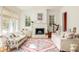 Bright living room featuring a decorative fireplace, large windows and stylish furnishings at 10528 Serenbe Ln, Chattahoochee Hills, GA 30268