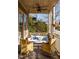 View of a covered porch with porch swing, chairs and pillows at 10528 Serenbe Ln, Chattahoochee Hills, GA 30268