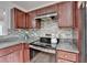 Close-up view of the kitchen featuring a stainless steel stove and granite countertops with decorative backsplash at 1284 Warsaw Rd, Roswell, GA 30076