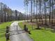 Gated driveway leading to a property with trees surrounding lush green grass on a sunny day at 5222 N Helton Rd, Winston, GA 30187