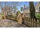 Backyard featuring a stone patio, wooden fence, mature trees, and steps leading up to a deck at 567 E Wesley Ne Rd, Atlanta, GA 30305