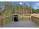 View of wooden back deck with grill overlooking backyard and wooded scenery at 972 Oakley Ln, Sugar Hill, GA 30518