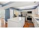 Open kitchen with white cabinets, stainless steel appliances, a central island, and hardwood flooring at 972 Oakley Ln, Sugar Hill, GA 30518