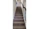 Carpeted staircase with dark railing, providing a comfortable transition between floors in the home at 3419 In Bloom Way, Auburn, GA 30011