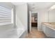 Bright bathroom with a soaking tub, a window with blinds, and a view into the primary bedroom at 461 Charleston Pl, Villa Rica, GA 30180