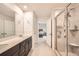 Bathroom featuring dual sink vanity with dark cabinets, glass shower, & bedroom access at 4929 Dufour Dr, Lilburn, GA 30047