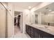 Bathroom featuring dual sink vanity with dark cabinets, large mirror and walk-in closet access at 4929 Dufour Dr, Lilburn, GA 30047