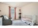 Cozy bedroom featuring soft gray carpet, a white crib, and a comfortable glider chair at 4929 Dufour Dr, Lilburn, GA 30047