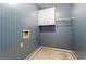 Small laundry room with blue striped wallpaper, cabinet, wire rack, and hookups for a washer and dryer at 10625 Haynes Forest Dr, Alpharetta, GA 30022