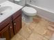 Bathroom featuring a brown vanity with white sink, toilet, and neutral-toned tile flooring at 5589 Dendy Trace, Fairburn, GA 30213