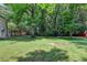 Lush backyard surrounded by mature trees providing privacy and a red outbuilding on a well-manicured lawn at 4253 Smithsonia Dr, Tucker, GA 30084