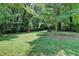 Large, lush backyard surrounded by mature trees and featuring a small red storage shed at 4253 Smithsonia Dr, Tucker, GA 30084