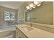 Bright bathroom with marble tile, quartz countertops, and tub with shower at 4253 Smithsonia Dr, Tucker, GA 30084