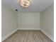 Neutral room featuring gray wood floors, white walls, and a modern light fixture at 4253 Smithsonia Dr, Tucker, GA 30084