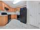 Kitchen featuring wood cabinets, tile flooring, and black appliances at 781 Courthouse Park Dr, Temple, GA 30179