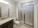 A well-lit bathroom featuring a shower with glass doors and granite countertop sink at 3308 Steeple Chase Sw Way, Conyers, GA 30094