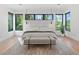 Modern bedroom with neutral tones, large windows, and bench at the foot of the bed at 2940 Old Peachtree Rd, Dacula, GA 30019