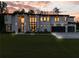 Stunning modern home exterior with expansive windows and a well-manicured lawn at dusk at 2940 Old Peachtree Rd, Dacula, GA 30019