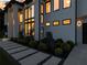 Modern home featuring a front entry, walkway lighting, lush landscaping, and oversized windows at 2940 Old Peachtree Rd, Dacula, GA 30019