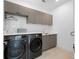 Modern laundry room with gray cabinetry, quartz countertops, stainless steel sink, and front-loading washer and dryer at 2940 Old Peachtree Rd, Dacula, GA 30019