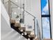 Modern staircase with glass railings and hanging crystal lighting, showcased by a large window view at 2940 Old Peachtree Rd, Dacula, GA 30019