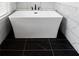 Freestanding tub with black marble floor and marble style tile extending up the wall at 403 Inglenook Walk, Marietta, GA 30060