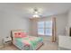 Bright bedroom featuring a ceiling fan, window with light pink curtains, and a colorful patchwork quilt at 5569 Snowy Orchid Dr, Sugar Hill, GA 30518