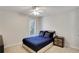 Neutral bedroom featuring a ceiling fan, window, and a bed with decorative blue pillows at 5569 Snowy Orchid Dr, Sugar Hill, GA 30518