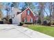 Side view of a well-maintained two-story brick home with white siding, large driveway, and landscaped lawn at 5569 Snowy Orchid Dr, Sugar Hill, GA 30518