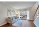 Cozy living room with hardwood floors, a comfortable sofa, large window with sheer curtains, and natural lighting at 5569 Snowy Orchid Dr, Sugar Hill, GA 30518