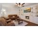 Cozy living room featuring a fireplace, built-in shelves, hardwood floors, and brown leather sofas at 5569 Snowy Orchid Dr, Sugar Hill, GA 30518